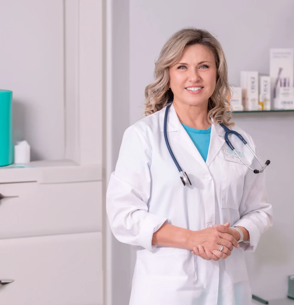 Elena Burdman, NP-C, a board-certified Nurse Practitioner and expert aesthetic injector at Injectable Aesthetics, smiling in her medical office.